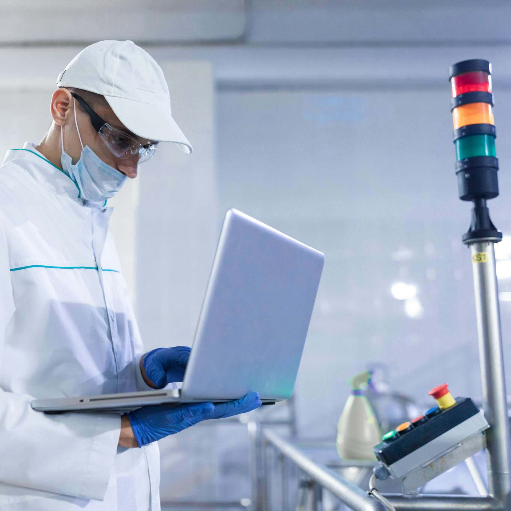 technologist with laptop in his hands make a set up of the production line while standing at the department of dairy factory